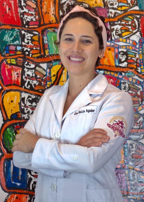 Dra. Raíza Aguiar sorrindo, de braços cruzados